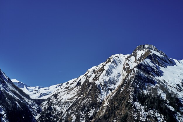 Schöne niedrige Winkelaufnahme eines Berges mit Schnee, der den Gipfel und den Himmel im Hintergrund bedeckt