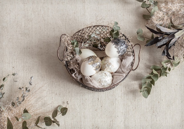 Schöne Ostereier in einem Korb, der mit getrockneten Blumen verziert wird. Frohe Ostern Konzept.