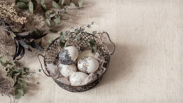 Schöne Ostereier in einem Korb, der mit getrockneten Blumen verziert wird. Frohe Ostern Konzept.