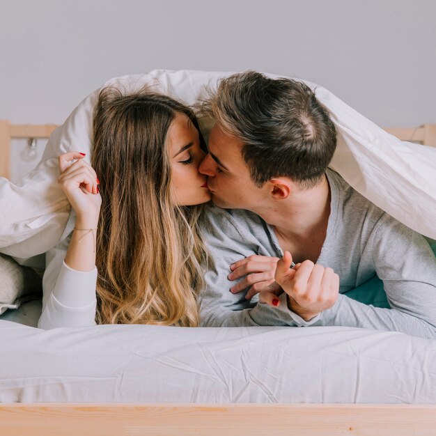 Schöne Paare, die auf Bett küssen