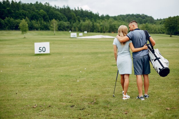 Schöne Paare, die Golf auf einem Golfplatz spielen