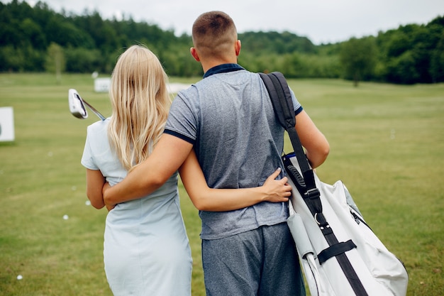 Schöne Paare, die Golf auf einem Golfplatz spielen