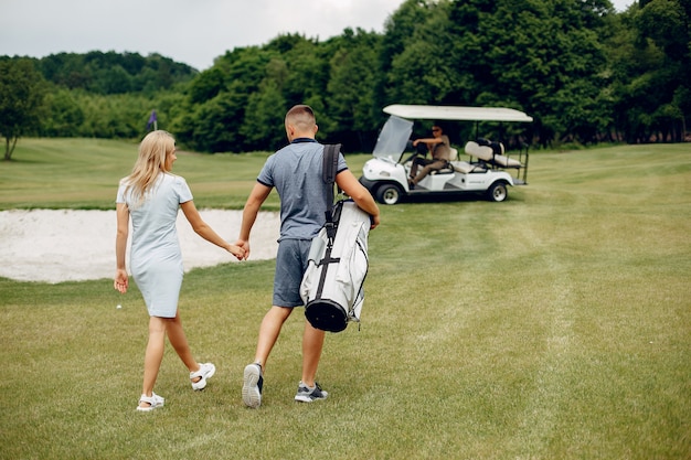 Schöne Paare, die Golf auf einem Golfplatz spielen