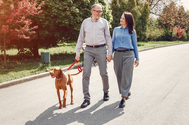 Schöne Paare in einem Sommerwald mit Hunde