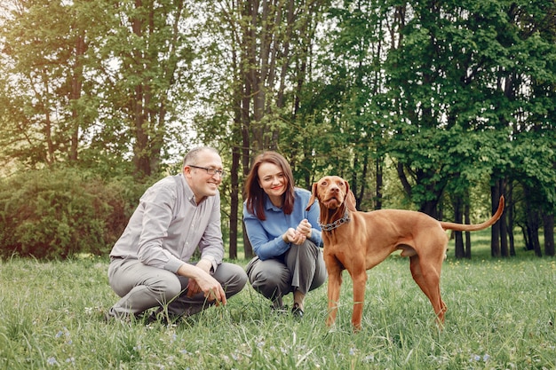 Schöne Paare in einem Sommerwald mit Hunde