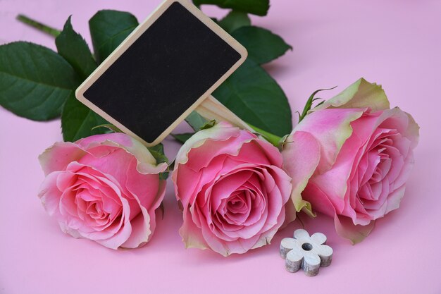 Schöne rosa Blumen mit einer hölzernen geformten Blume auf einer rosa Oberfläche