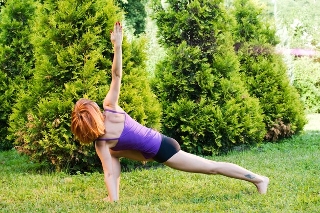 Schöne rote Frau macht Fitness oder Yoga-Übungen