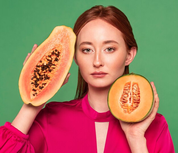 Schöne rothaarige Frau, die eine Melone hält