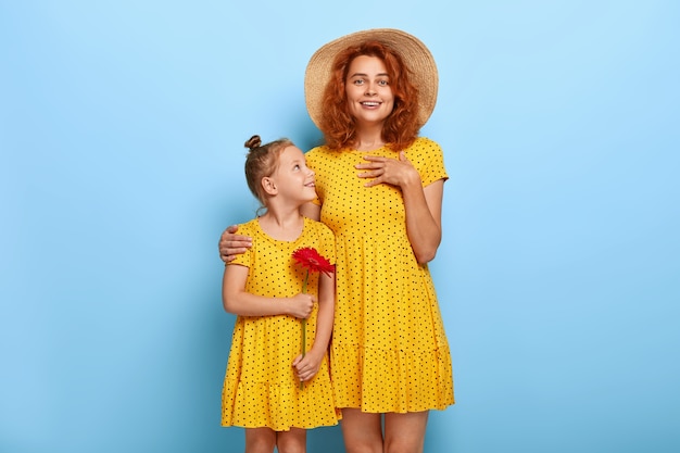 Schöne rothaarige Mutter und Tochter posieren in ähnlichen Kleidern