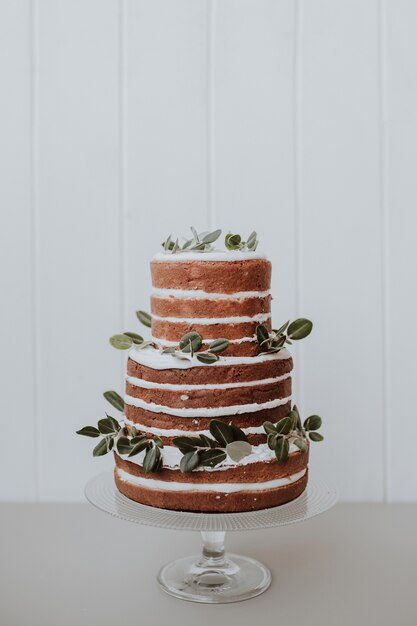 schöne rustikale Hochzeitstorte verziert mit Eukalyptus auf weißem hölzernem Hintergrund