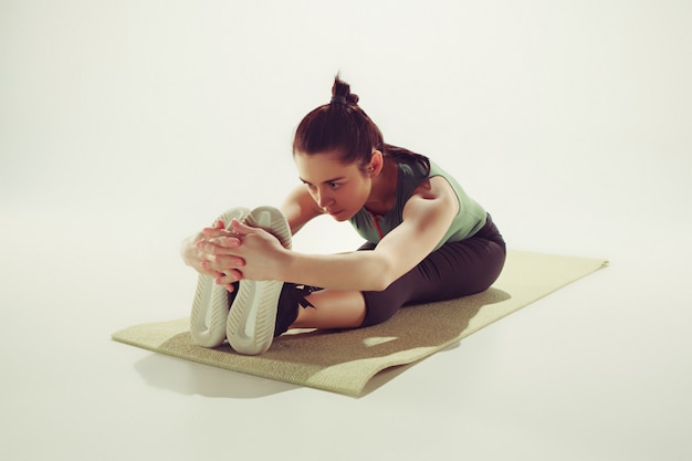 Schöne schlanke Brünette, die einige Dehnübungen in einem Fitnessstudio macht