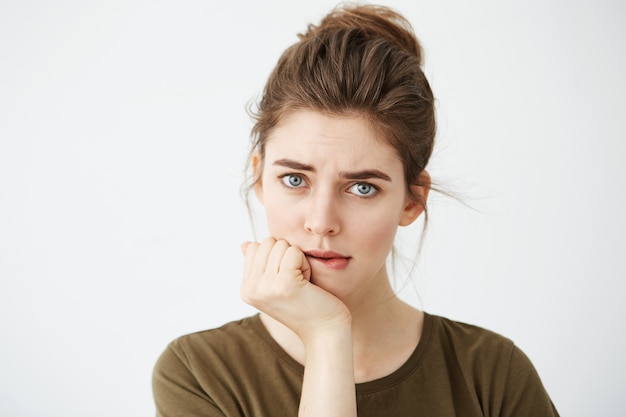 Schöne schüchterne junge Frau mit Haarknoten denken beißende Lippe.