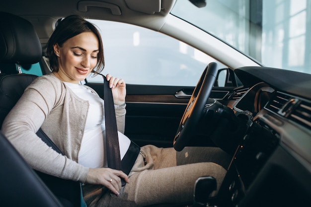 Schöne schwangere Frau, die im Auto fährt