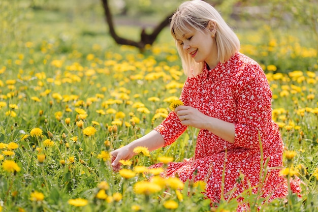 Schöne schwangere Frau, die im Park das rote Kleid trägt