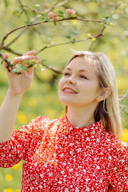 Schöne schwangere Frau, die im Park das rote Kleid trägt