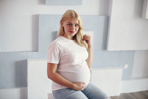 Schöne schwangere Frau mit dem dicken Bauch in einem Studio