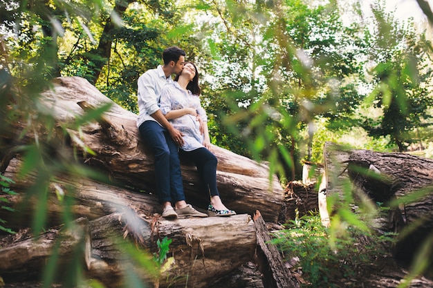 Schöne schwangere Paare, die sich draußen im Wald entspannen