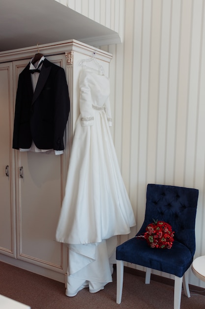 Schöne schwarze Bräutigamjacke und Braut kleiden das Hängen im Hotelzimmer