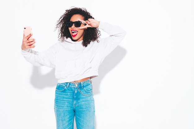 Schöne schwarze Frau mit Afrolockenfrisur. Lächelndes Modell in Sommerkleidung