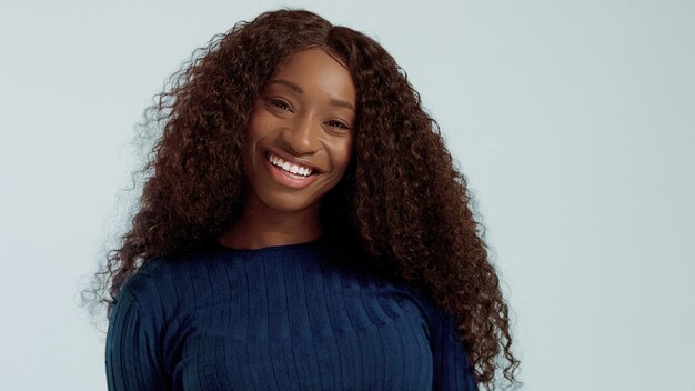 Schöne schwarze gemischtrassige Afroamerikanerin mit langen lockigen Haaren und perfektem Lächeln