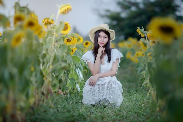 schöne sexy Frau in einem weißen Kleid auf einem Feld von Sonnenblumen, gesunder Lebensstil