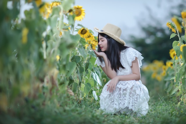 schöne sexy Frau in einem weißen Kleid auf einem Feld von Sonnenblumen, gesunder Lebensstil