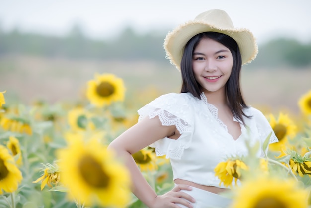 schöne sexy Frau in einem weißen Kleid zu Fuß auf einem Feld von Sonnenblumen