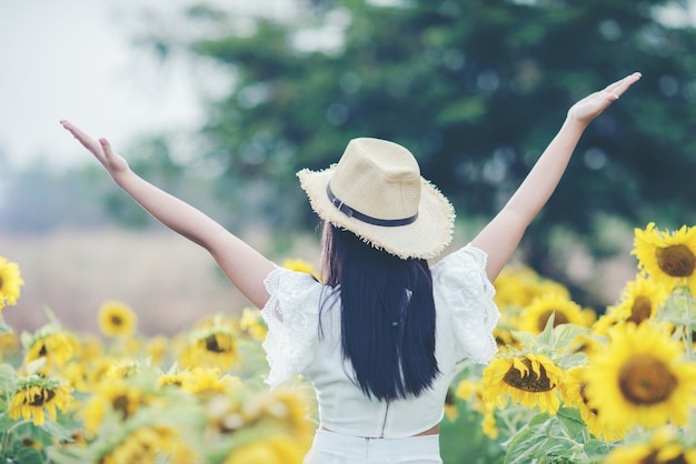 schöne sexy Frau in einem weißen Kleid zu Fuß auf einem Feld von Sonnenblumen