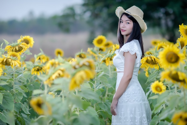 schöne sexy Frau in einem weißen Kleid zu Fuß auf einem Feld von Sonnenblumen