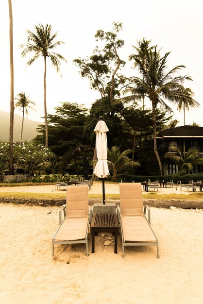 Schöne Silhouette Luxus Regenschirm und Stuhl um Schwimmbad im Hotel Pool Resort mit Kokosnuss Palme bei Sonnenaufgang Zeiten - Vintage Filter und Boost up Farbe Verarbeitung