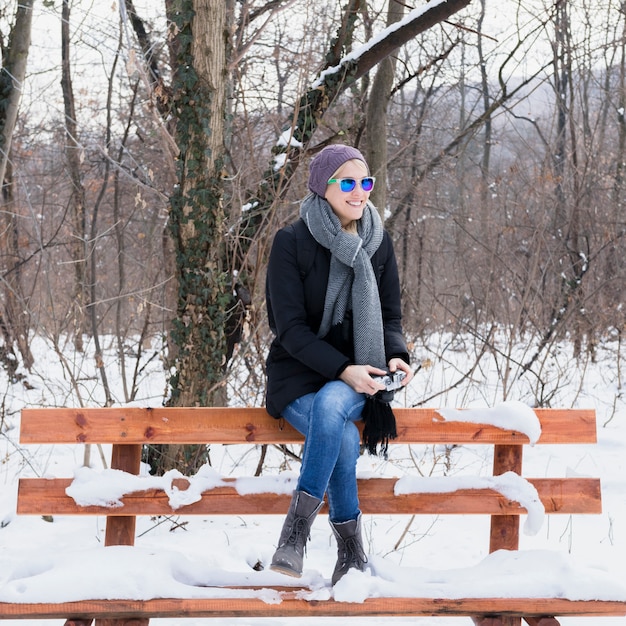 Schöne sitzende Bank der jungen Frau mit Schnee