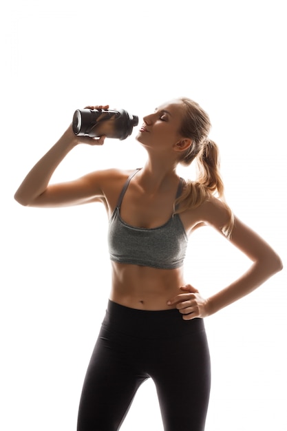 Kostenloses Foto schöne sportliche frau, die flasche hält und aufwirft