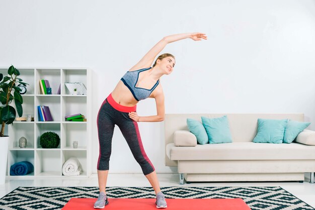 Schöne sportliche junge Frau, die im modernen Wohnzimmer trainiert