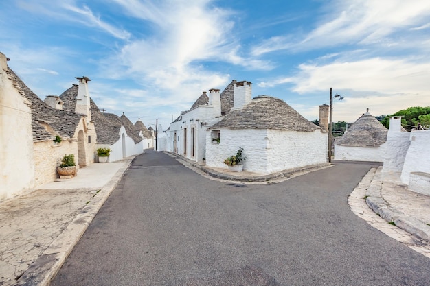 Schöne Stadt Alberobello mit Trulli-Häusern zwischen grünen Pflanzen und Blumen, Haupttouristenviertel, Region Apulien, Süditalien. Typische Gebäude mit Trockenmauern und konischem Dach