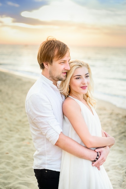 Schöne stilvolle Paare, die auf dem Strand aufwerfen