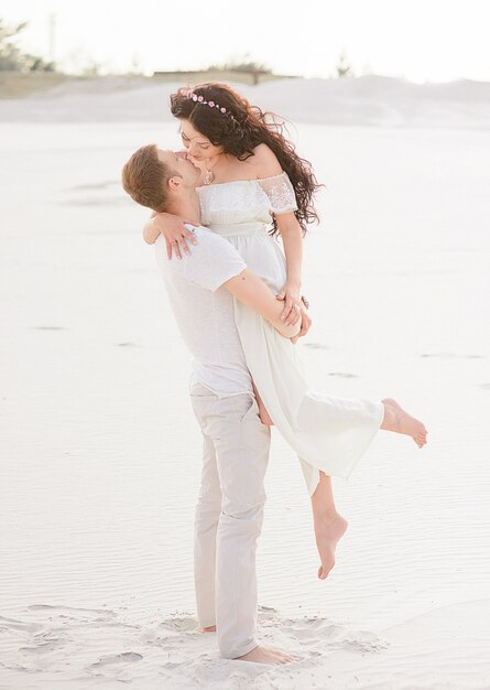 Schöne stilvolle Paare, die auf dem Strand aufwerfen