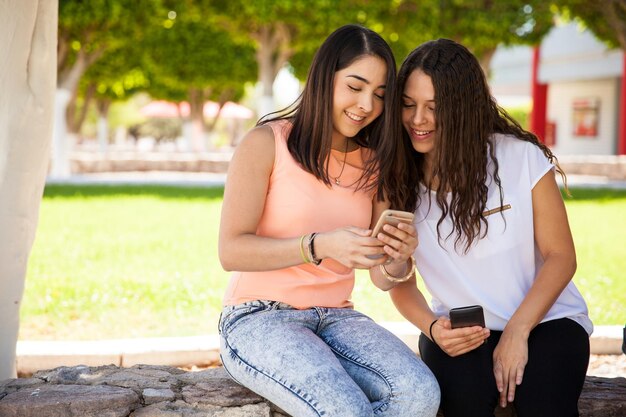 Schöne Studenten, die auf ein Smartphone schauen und Informationen austauschen