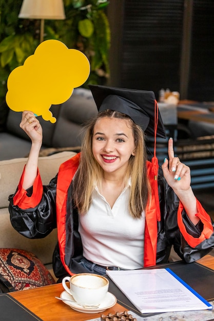 Schöne Studentin, die Ideentafel hält und ihren Finger hebt, während sie in die Kamera lächelt