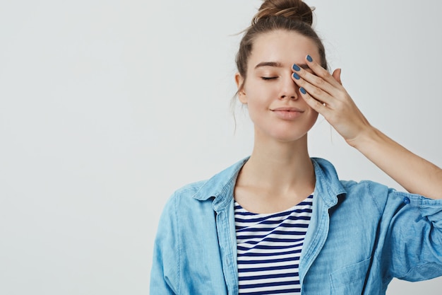 Schöne Teenagerfrau, die ein Auge mit ihrer Hand bedeckt