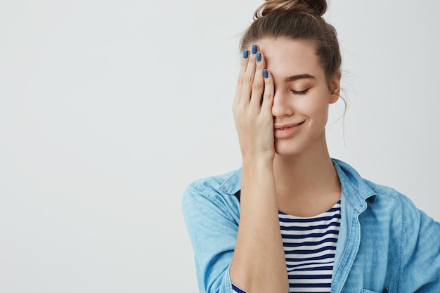 Schöne Teenagerfrau, die ein Auge mit ihrer Hand bedeckt