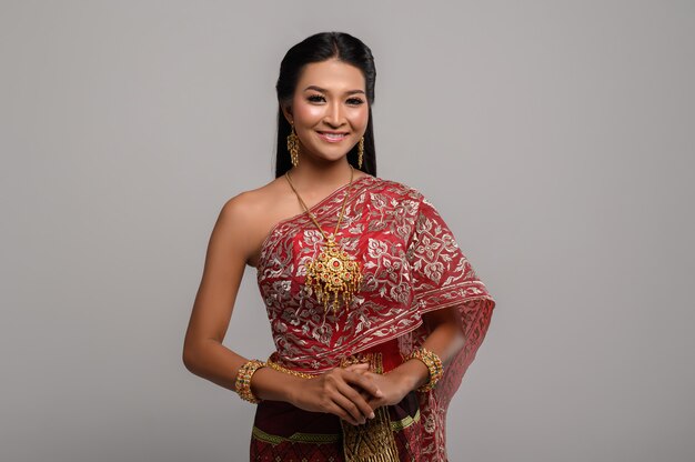 Schöne thailändische Frau, die ein thailändisches Kleid und ein glückliches Lächeln trägt.