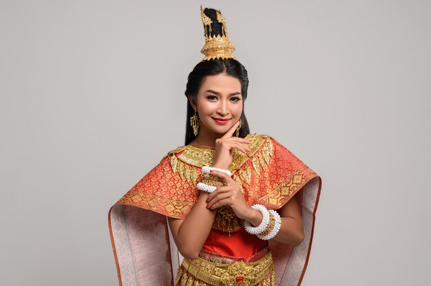 Schöne thailändische Frau, die ein thailändisches Kleid und ein glückliches Lächeln trägt.