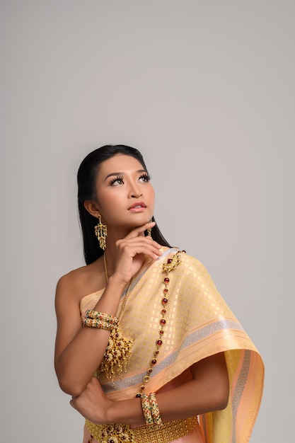 Schöne thailändische Frau, die thailändisches Kleid trägt und die Spitze betrachtet