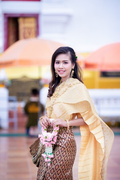 Schöne thailändische Frau im thailändischen traditionellen Kostüm am Tempel