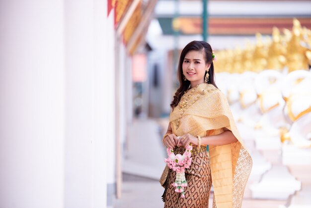 Schöne thailändische Frau im thailändischen traditionellen Kostüm am Tempel