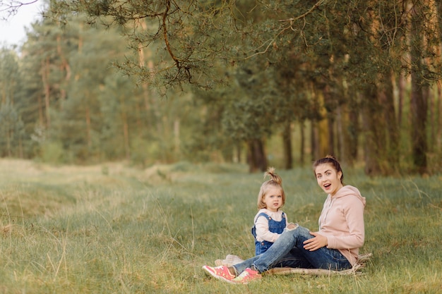 Schöne und glückliche Mutter und Tochter, die eine gute Zeit im Wald haben