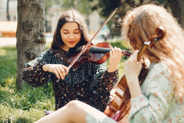 Schöne und romantische Mädchen in einem Park mit einer Violine