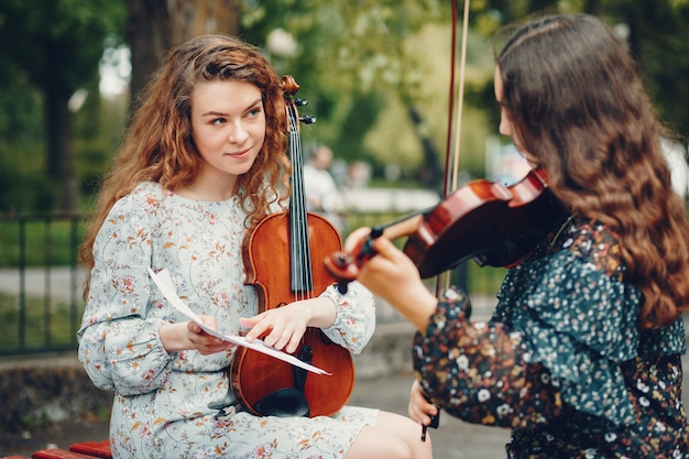 Schöne und romantische Mädchen in einem Park mit einer Violine
