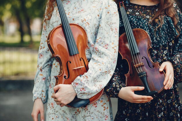 Schöne und romantische Mädchen in einem Park mit einer Violine