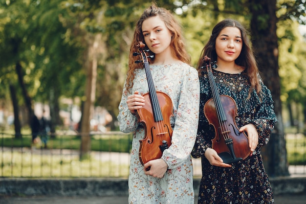 Schöne und romantische Mädchen in einem Park mit einer Violine